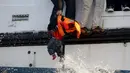 Seorang Imigran saat akan menyerahkan  bayi untuk diselamatkan oleh petugas karena perahu yang ditumpangi mereka akan karam di Laut Aegea, Yunani, 30 Oktober 2015. (REUTERS/Giorgos Moutafis)
