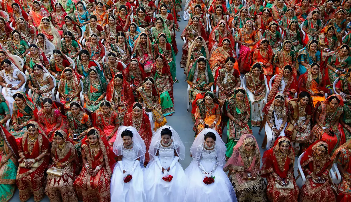 Pengantin perempuan duduk bersama saat nikah massal di Surat, India, Minggu (23/12). Nikah massal bagi perempuan yatim ini digelar oleh pengusaha berlian asal India, Mahesh Savani. (AP/Ajit Solanki)