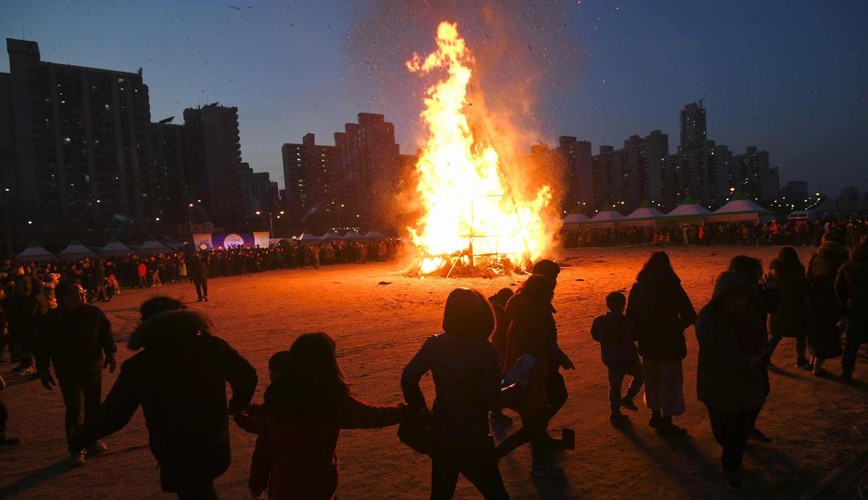 Warga Korea Selatan berkumpul di dekat api unggun besar dalam sebuah acara perayaan "Jeongwol Daeboreum" (Bulan Purnama) di sebuah taman di Seoul, Korea Selatan (1/3). (AFP Photo/Jung Yeon-je)