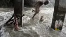 Sejumlah anak bermain di sungai dengan arus yang sangat deras akibat hujan lebat di bawah jembatan di Manila, Filipina (11/6). (AFP Photo/Noel Celis)