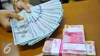 Petugas menunjukkan mata uang dolar dan mata uang rupiah di penukaran uang di Jakarta, Rabu (9/11). Nilai tukar rupiah terhadap dolar Amerika Serikat (AS) pada saat jeda siang ini kian terpuruk di zona merah. (Liputan6.com/Angga Yuniar)