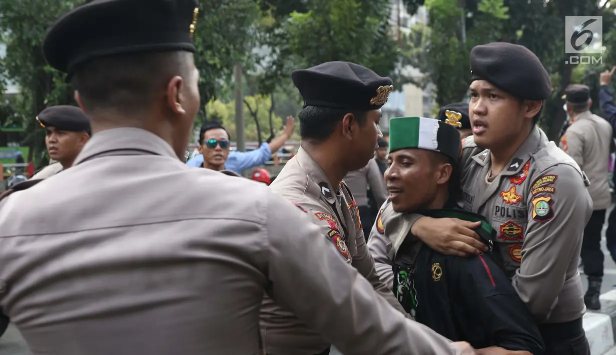 Aparat kepolisian mengamankan salah satu massa yang mengaku dari Himpunan Mahasiswa Islam unjuk rasa di depan Gedung KPK, Jakarta, Rabu (18/9/2019). Dalam aksinya, mereka menolak pimpinan KPK terpilih periode 2019-2023. (Liputan6.com/Helmi Fithriansyah)