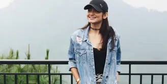 Enzy Storia tampil mengenakan oversize denim sebagai outer dipadukan inner hitam serasi dengan kalung choker yang saat itu tengah tren. Ia memadukannya dengan mini skirt hitam putih motif tribal dan mengenakan topi cap hitam.  [@enzystoria]