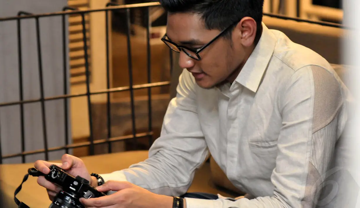 Afgan tampak melihat hasil foto-foto yang telah diambil oleh seorang wartawan. (Liputan6.com/Panji Diksana)