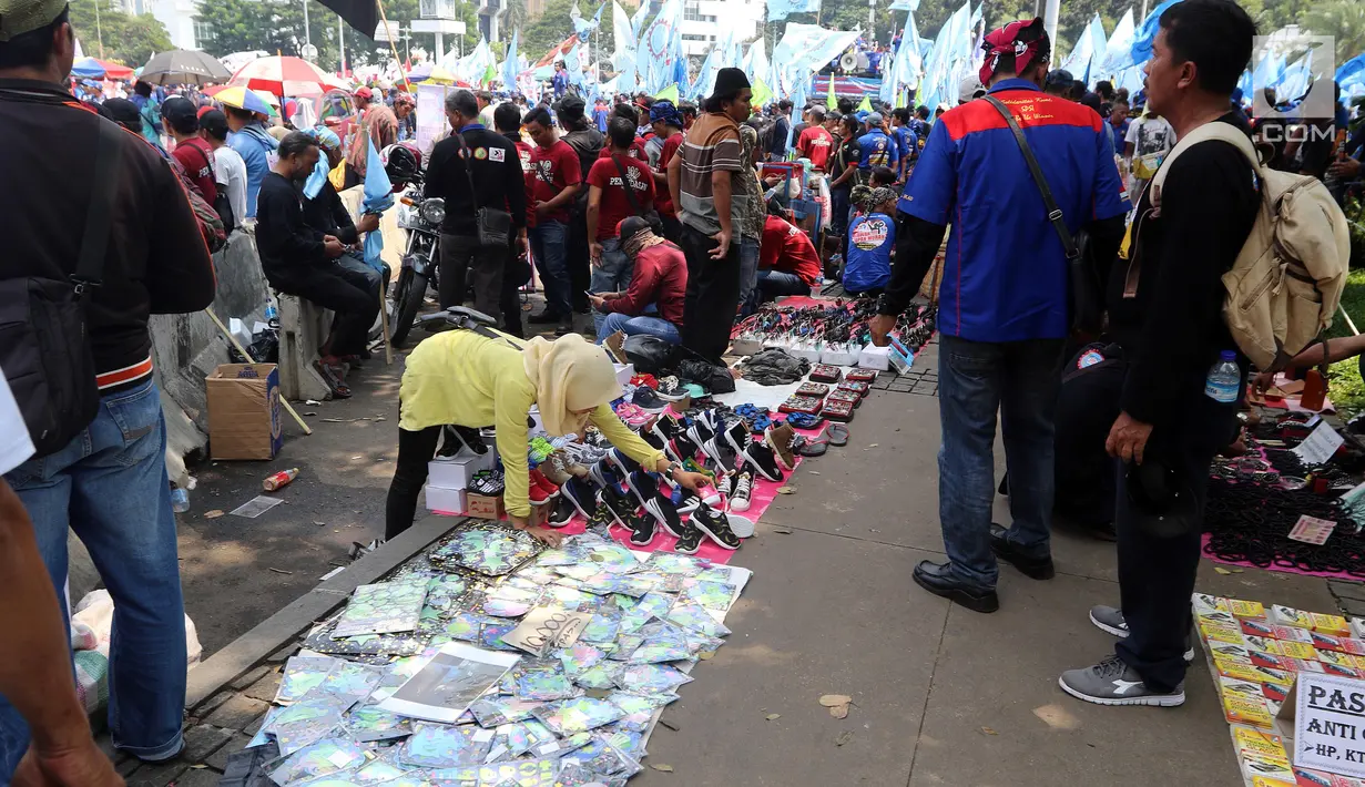 Pedagang kaki lima menjajakan barang dagangan saat Demo Hari Buruh di Jakarta, Selasa (1/5). Pedagang kaki lima ini memanfaatkan Hari Buruh untuk mengais rejeki dengan berjualan saat demontrasi berlangsung. (Liputan6.com/Johan Tallo)