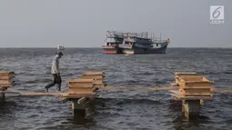 Pekerja menyelesaikan pondasi dermaga di Muara Angke, Jakarta Utara, Rabu (3/7/2019). Pemprov DKI Jakarta membangun dermaga dengan panjang mencapai 300 meter dengan lebar sekitar tujuh meter dilengkapi dengan jembatan penghubung serta pemecah ombak sepanjang 480 meter. (Liputan6.com/Faizal Fanani)
