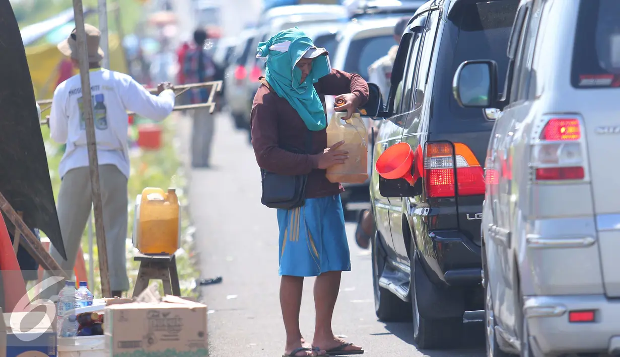 Warga mengisikan bensin kepada pemudik di pintu tol Brebes Timur, Minggu (3/7).Pemudik yang telah mengantri berjam-jam dan kekurangan BBM akhirnya akan membeli bensin yang dijual oleh warga sekitar tersebut. (Liputan6.com/Angga Yuniar)