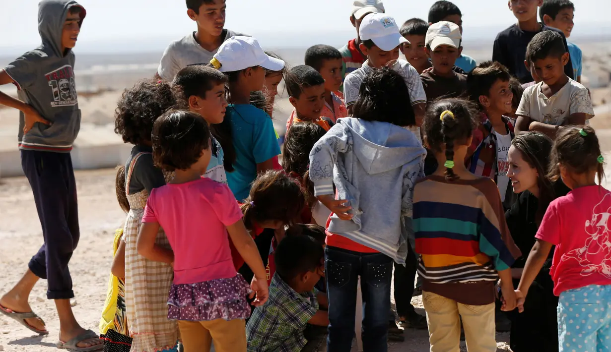 Aktris Angelina Jolie berbicara dengan anak-anak pengungsi Suriah setelah konferensi pers di kamp pengungsi Azraq untuk Suriah yang mengungsi akibat konflik, dekat kota Al Azraq, Yordania, Jumat (9/9). (REUTERS / Muhammad Hamed)
