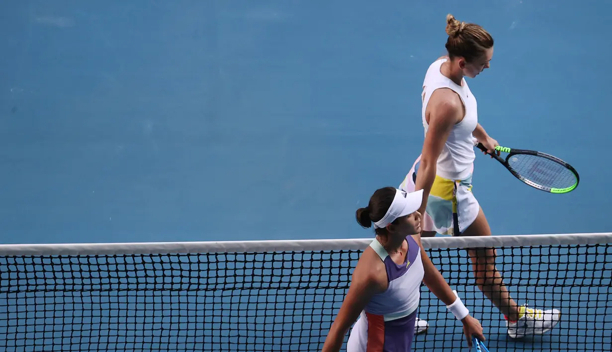 Petenis Rumania, Simona Halep (atas) dan Garbine Muguruza dari Spanyol meninggalkan lapangan setelah pertandingan semifinal tunggal putri Australia Terbuka di Melbourne, Australia, Kamis (30/1/2020). Halep gagal ke final Australia Terbuka 2020 usai kalah dari Muguruza 7-6, 7-5. (DAVID GREY/AFP)