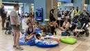 Para turis menunggu di aula keberangkatan bandara saat evakuasi sedang berlangsung akibat kebakaran hutan, di pulau Rhodes, Yunani, Minggu (23/7/2023). (Will VASSILOPOULOS / AFP)