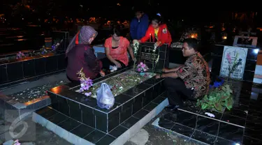 Warga keturunan Portugis melakukan tabur bunga saat ziarah ke makam yang terdapat di sebelah Gereja Tugu, Jakarta, Kamis (24/12). Tradisi nyekar itu dilakukan usai mengikuti ibadah kebaktian malam Natal di gereja. (Liputan6.com/Gempur M Surya)