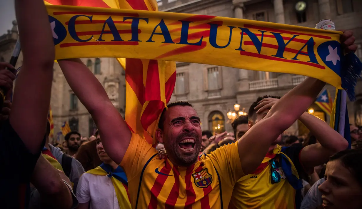 Seorang pria bersorak setelah Parlemen Catalonia mendeklarasikan kemerdekaan dari Spanyol di luar Gedung Palau Generalitat, Barcelona, Jumat (27/10). Sejumlah masyarakat pendukung kemerdekaan, turun ke jalan dan meneriakkan 'Liberty'. (AP/Santi Palacios)