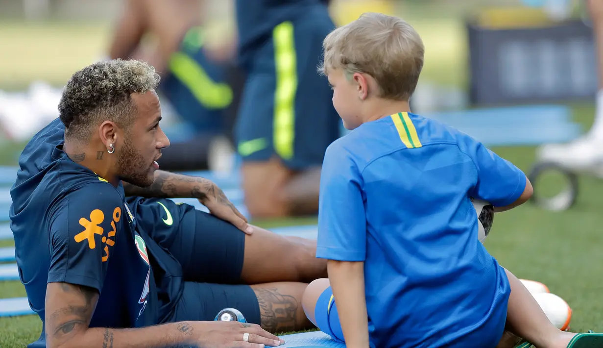 Pemain Brasil, Neymar berbicara dengan putranya, Davi Lucca di sela sesi latihan di Sochi, Rusia, Jumat (29/6). Neymar mengajak putranya saat mengikuti latihan bersama Timnas Brasil di Piala Dunia 2018. (AP Photo/Andre Penner)