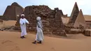 Seorang pemandu (kiri) berbicara dengan pengunjung di situs arkeologi Meroe di Bejrawiya, Sudan, Minggu, 2 Agustus 2026. (Foto AP/Mohnd Blal)