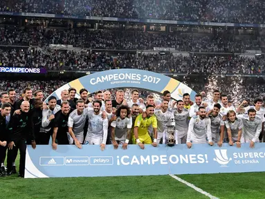 Para pemain Real Madrid berpose dengan trofi merayakan kemenangan atas Barcelona pada Piala Super Spanyol 2017 di stadion Santiago Bernabeu, Spanyol (16/8). Real Madrid menang 2-0 atas Barcelona dengan skor agregat 5-1. (AFP Photo/Javier Soriano)