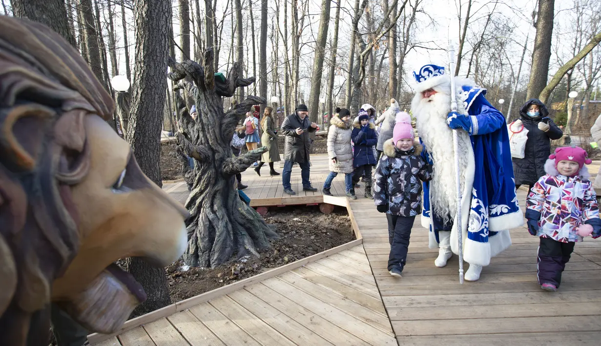 Seorang staf yang mengenakan kostum karakter dongeng Rusia, Kakek Frost, berjalan bersama anak-anak dalam pembukaan "Jalur Dongeng" di "Kediaman Kakek Frost" di Moskow, Rusia (18/11/2020). . (Xinhua/Alexander Zemlianichenko Jr)