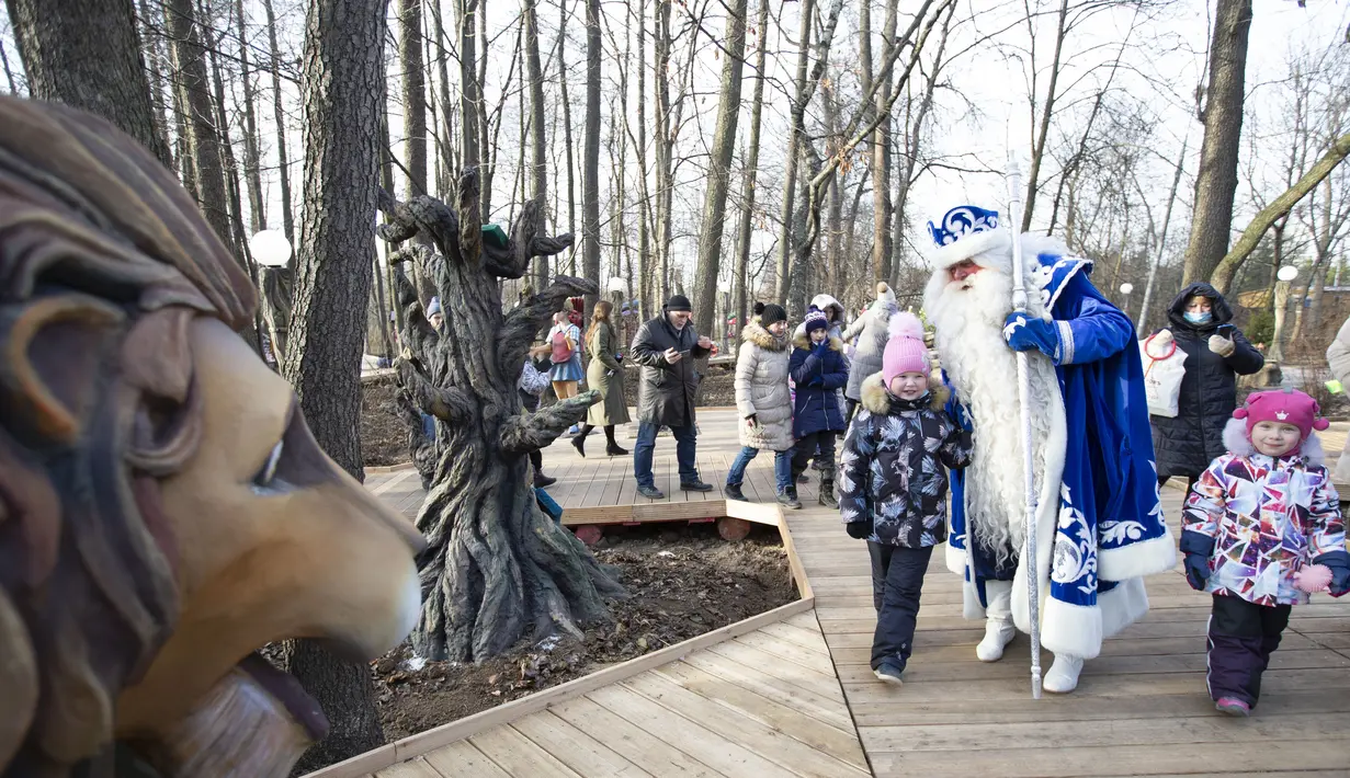 Seorang staf yang mengenakan kostum karakter dongeng Rusia, Kakek Frost, berjalan bersama anak-anak dalam pembukaan "Jalur Dongeng" di "Kediaman Kakek Frost" di Moskow, Rusia (18/11/2020). . (Xinhua/Alexander Zemlianichenko Jr)