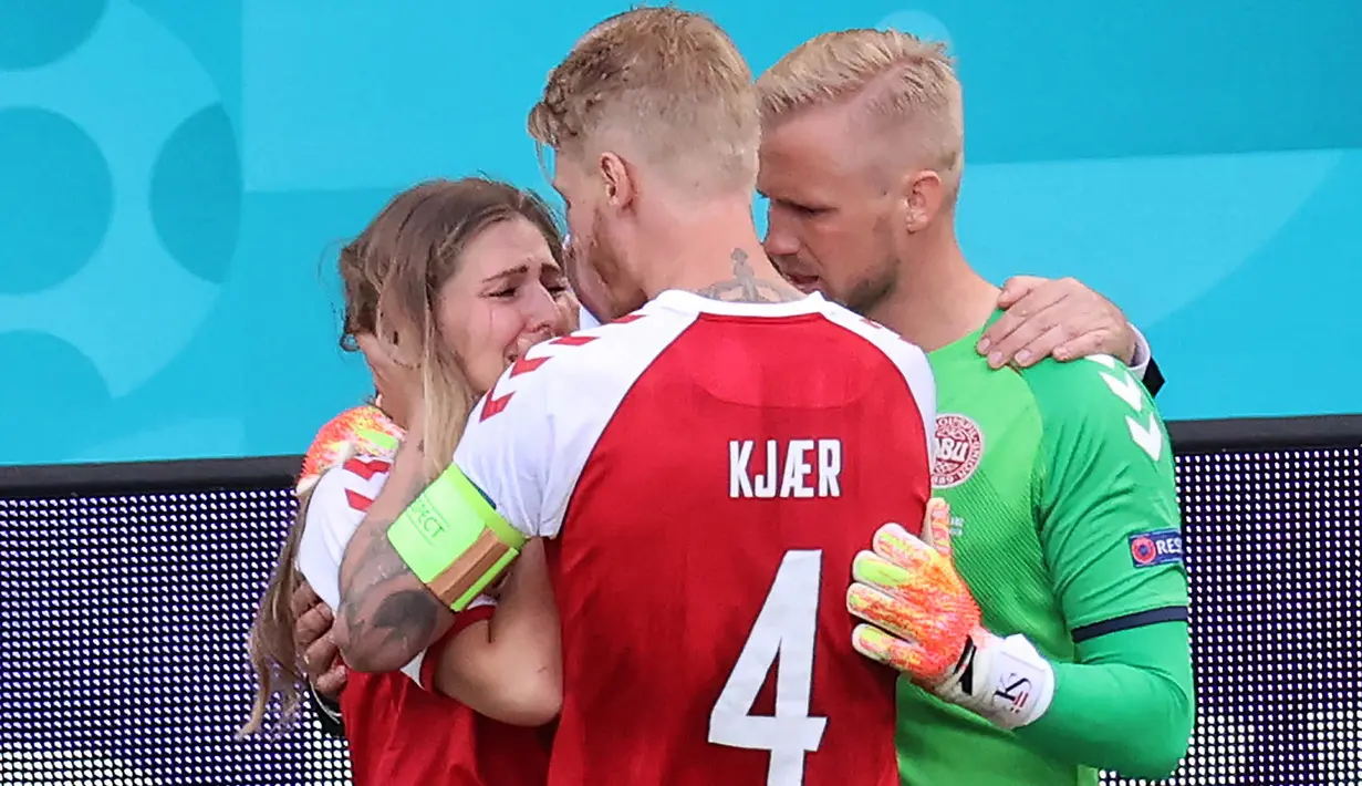 Segera setelah mengetahui bahwa Christian Eriksen kolaps, Simon Kjaer dan Kasper Schmeichel pun langsung menghampiri istri dari rekannya tersebut dan berusaha menenangkannya. (Foto: AFP/Pool/Wolfgang Rattay)