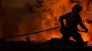 Seorang petugas pemadam kebakaran dengan Cal Fire Santa Clara Unit menyeret selang saat memerangi Mosquito Fire dekat Michigan Bluff di Placer County, California, Amerika Serikat, 7 September 2022. (Stephen Lam/San Francisco Chronicle via AP)