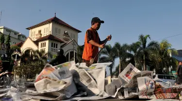 Petugas membersihkan sampah koran di ruas Jalan Jatinegara Barat, Jakarta, Jumat (17/7/2015). Lembaran koran bekas ditinggalkan begitu saja pasca pelaksanaan salat Hari Raya Idul Fitri 1436 H. (Liputan6.com/Johan Tallo)