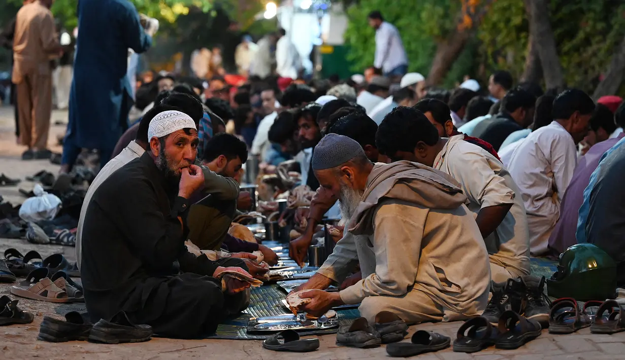 Orang-orang yang membutuhkan makan makanan yang disediakan oleh para donor amal di Islamabad, Pakistan pada tanggal 2 Mei 2023. (Photo by Aamir QURESHI / AFP)