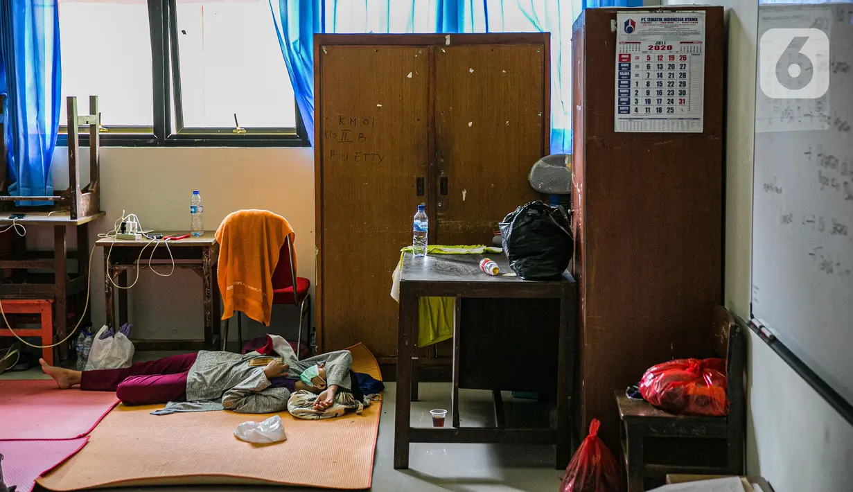 Seorang korban banjir beristirahat di salah ruang kelas di gedung SDN 01/02 Kampung Melayu, Jakarta, Selasa (9/2/2021). Gedung sekolah di Kebon Pala tersebut menjadi salah satu posko pengungsian bagi sebagian korban banjir Kampung Melayu. (Liputan6.com/Faizal Fanani)