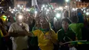 Demonstran menyalakan lampu kilat ponsel mereka saat menggelar aksi protes di Rio de Janeiro, Brasil (3/4). Dalam aksinya mereka menolak permintaan mantan Presiden Brasil da Silva untuk keluar dari penjara. (AP / Silvia Izquierdo)