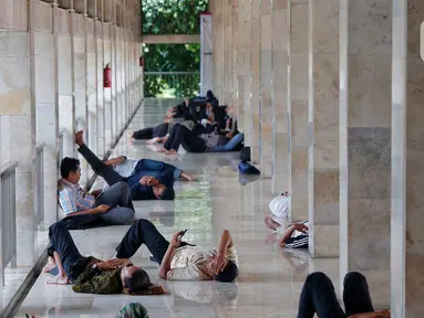 Sejumlah umat muslim yang tengah berpuasa beristirahat usai melaksaanakan shalat Jumat di Istiqlal, Jakarta, Jumat (24/3/2023). (Liputan6.com/Angga Yuniar)