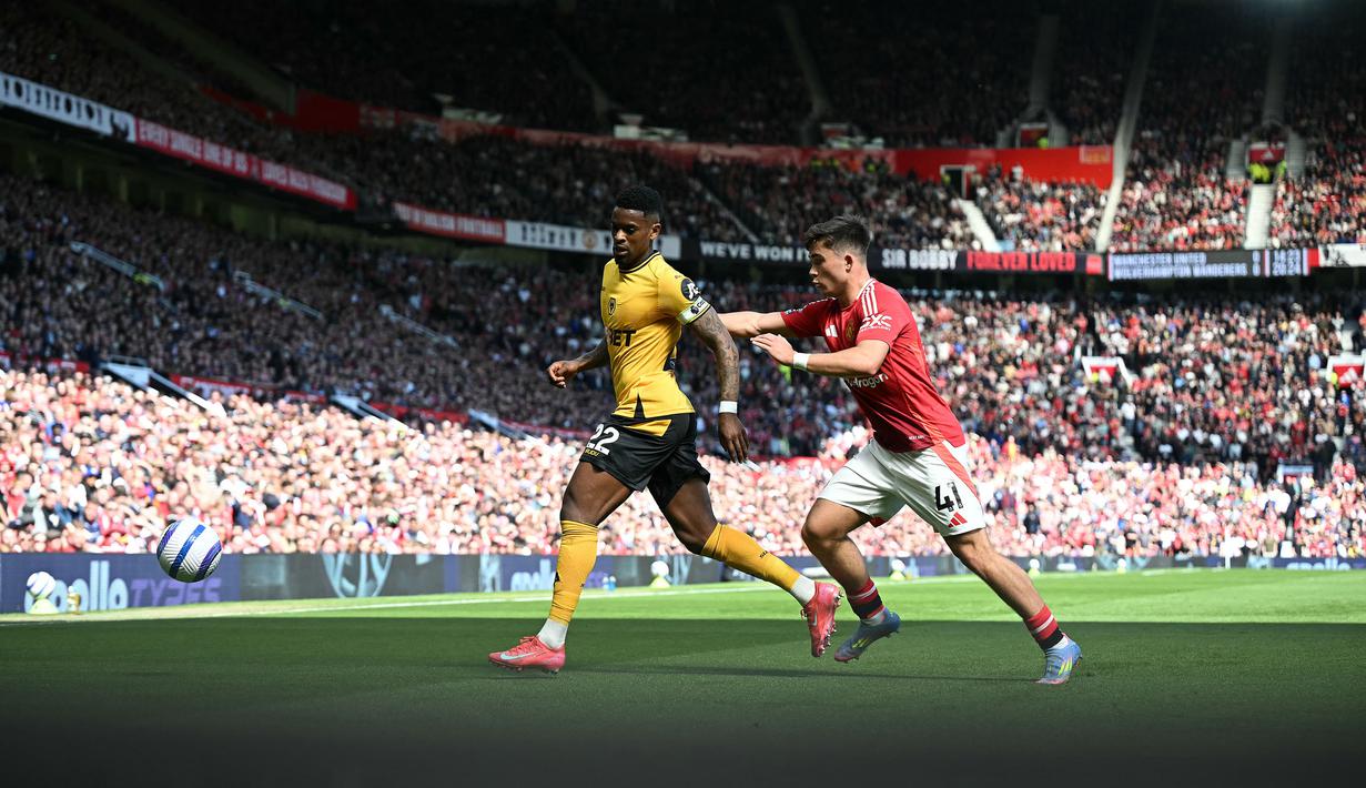 Pemain Manchester United, Harry Amass (kanan) membayangi pergerakan pemain Wolves, Nelson Semedoduring dalam laga lanjutan Liga Inggris 2024/2025 di Old Trafford, Inggris, Minggu (20/04/2025) waktu setempat. (AFP/Paul Ellis)