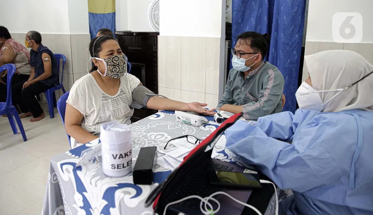 Petugas Puskemas Kampung Melayu memeriksa kesehatan warga Kebon Pala saat pelaksanaan vaksinasi COVID-19, Jakarta, Jumat (18/6/2021). Presiden Joko Widodo mengingatkan Pemprov DKI Jakarta untuk mengejar target vaksinasi 7,5 juta warga sampai Agustus 2021. (Liputan6.com/Faizal Fanani)