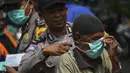 Petugas polisi memasangkan masker kepada warga saat kabut asap tebal menyelimuti wilayah Banda Aceh (25/9/2019). PBB memperingatkan pada 24 September, ketika para ilmuwan mengatakan api melepaskan sejumlah besar gas rumah kaca yang merusak iklim. (AFP Photo/Chaideer Mahyuddin)