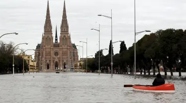 Warga menggunakan perahu saat melihat kondisi banjir di depan Basilika Lujan, Argentina, Rabu (12/8/2015). Lebih dari 20.000 orang telah dievakuasi setelah hujan lebat di akhir pekan lalu yang menyebabkan sungai naik dan banjir. (REUTERS/Marcos Brindicci)