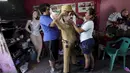 Dua orang pekerja memasangkan topi ke boneka raja narkoba Joaquin "El Chapo" Guzman saat menyelesaikannya di Reynosa, Meksiko (21/7/2015). Guzman melarikan diri dari penjara melalui terowongan yang ia buat pada bulan lalu. (REUTERS/Daniel Becerril)