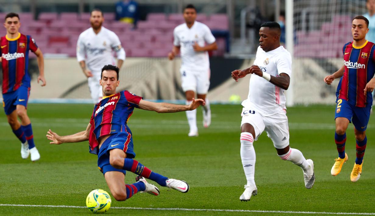 Gelandang Barcelona Sergio Busquets dan penyerang Real Madrid, Vinicius Junior berebut bola pada laga La Liga bertajuk El Clasico di Nou Camp, Sabtu (24/10/2020). Barcelona harus menelan pil pahit kalah 1-3 dari musuh bebuyutannya Real Madrid di kandang sendiri, Nou Camp. (AP Photo/Joan Monfort)
