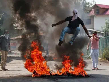 Demonstran melompati api saat aksi di Srinagar, India, Selasa (13/9). Mereka protes karena pembunuhan yang terjadi di Kashmir belum lama ini. (REUTERS / Danish Ismail)