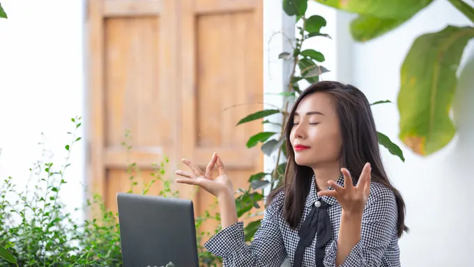 Seorang perempuan sedang melakukan pose meditasi di kantor (Foto Dok: Freepik/jcomp)