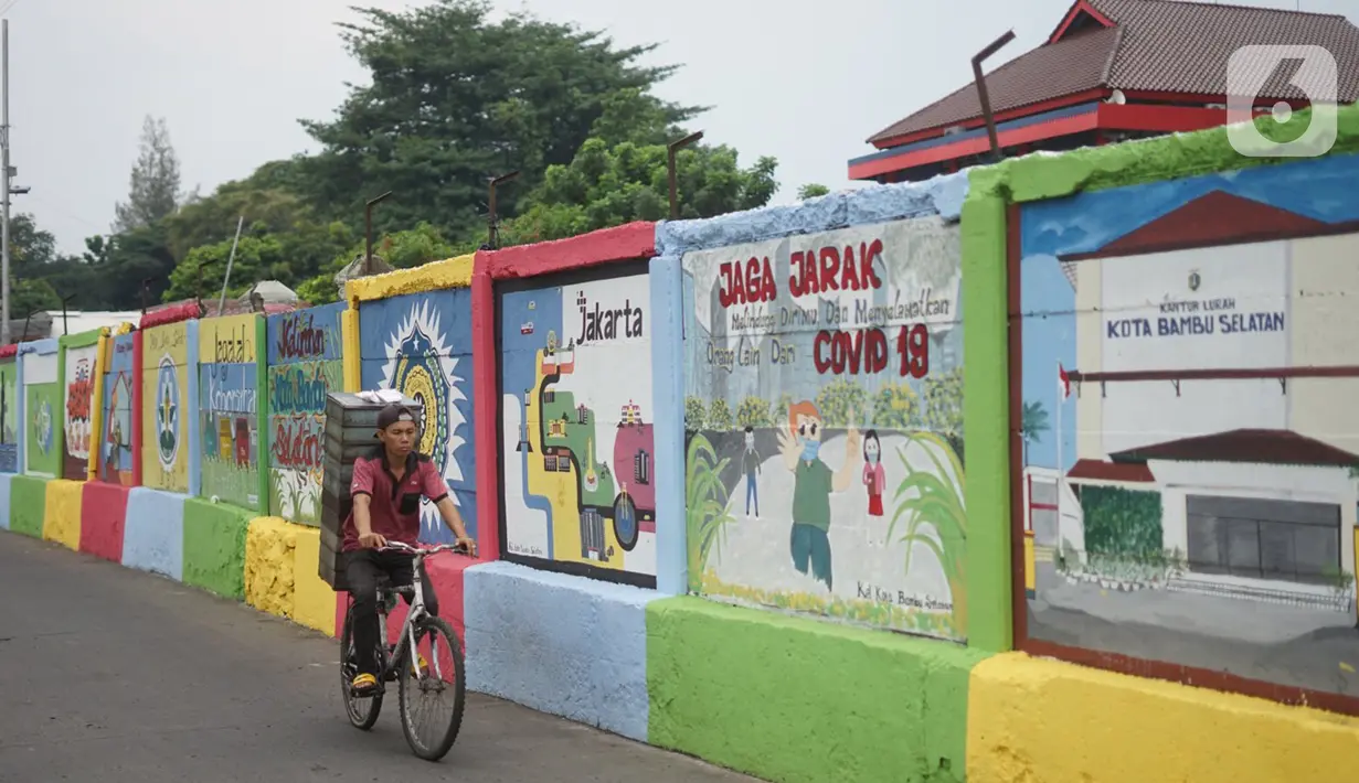 Pedagang melintas di depan mural bertema Kota Jakarta di sekitar Rusunawa KS Tubun, Jakarta, Senin (23/11/2020). Mural tersebut dibuat guna memercantik lingkungan di sekitar rusun agar lebih berwarna dan tidak tampak kumuh. (Liputan6.com/Immanuel Antonius)