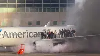 Evakuasi penumpang di sayap pesawat American Airlines setelah terbakar di gerbang Bandara Internasional Denver di Denver, Colorado, 13 Maret 2025. ( AFP/Branden Williams)