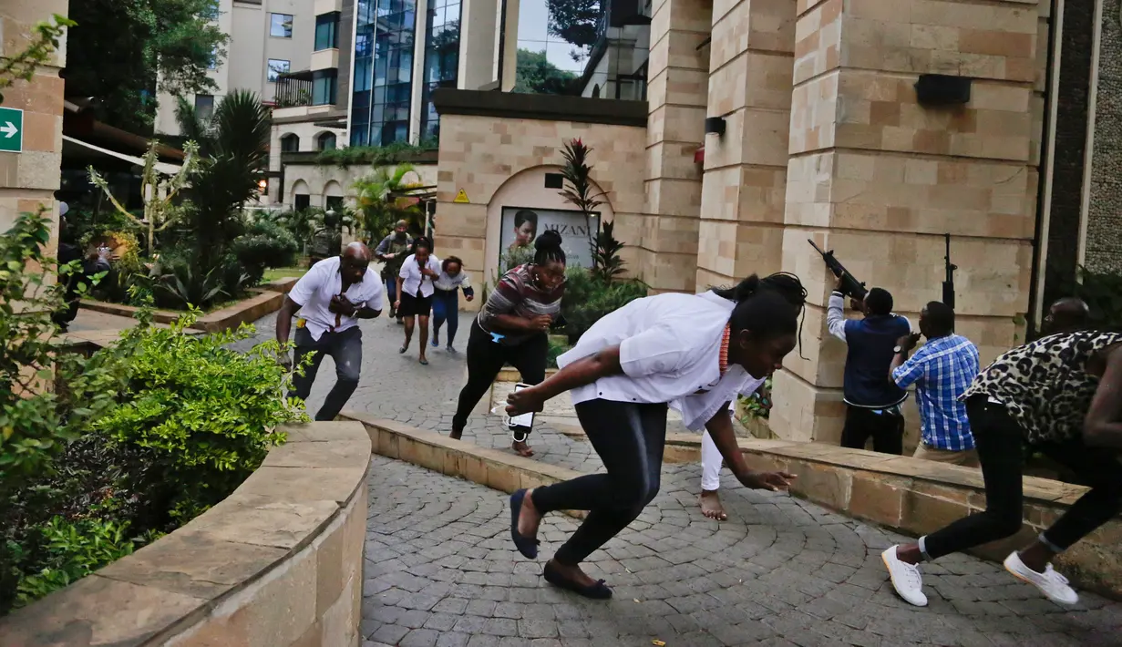 Warga melarikan diri saat pasukan keamanan memburu kelompok bersenjata yang menyerang sebuah kompleks hotel mewah di Nairobi, Kenya, Selasa (15/1). Polisi Kenya dibantu pasukan asing untuk melumpuhkan kelompok bersenjata. (AP Photo/Khalil Senosi)