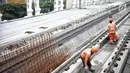 Pekerja menyelesaikan proyek pembangunan Light Rail Transit (LRT) Jabodebek di Stasiun LRT TMII, Jakarta, Senin (14/1). Stasiun LRT TMII yang dibangun dua lantai sudah mencapai 40%. (Liputan6.com/Faizal Fanani)