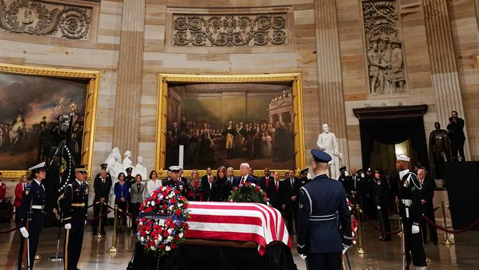 Presiden AS Donald Trump dan Melania Trump memberikan penghormatan terakhir kepada George HW Bush di Gedung Capitol, Washington, Senin (3/12). Jenazah Presiden ke-41 AS itu disemayamkan di Rotunda Capitol Hill selama beberapa hari. (MANDEL NGAN/ AFP)