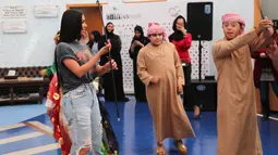 Kim Kardashian menyaksikan anak-anak menari saat kunjungannya di Rashid Media Centre, Dubai (16/1). Selama kunjungannya, Kim Kardashian menyaksikan sebuah film dokumenter tentang sejarah kota tersebut. (AFP Photo And Rashid Media Center/Stringer)
