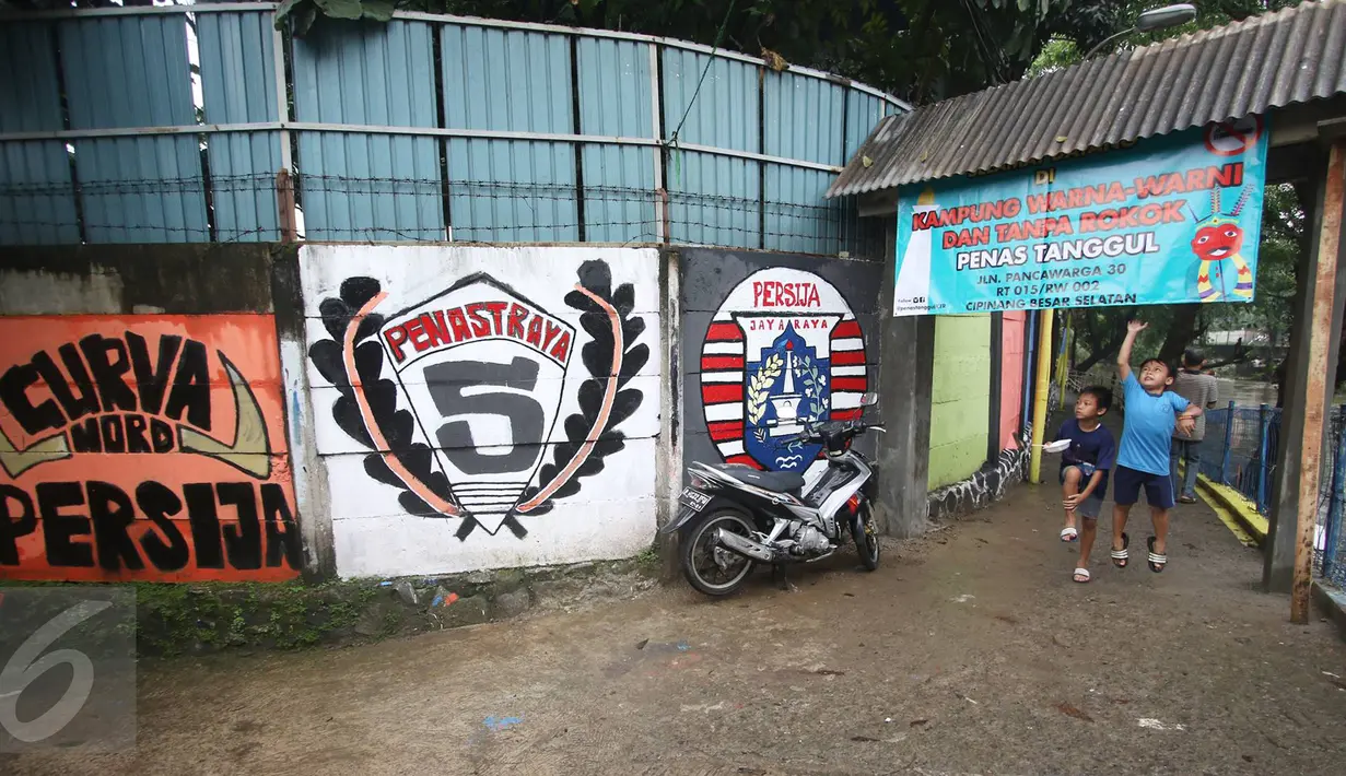 Anak-anak berdiri di bawah spanduk Kampung Penas Tanggul, Cipinang Besar Selatan, Jakarta, Kamis (23/3). Kampung warna-warni tanpa rokok itu dibuat oleh warga sebagai bentuk upaya perlindungan bagi perempuan dan anak. (Liputan6.com/Immanuel Antonius)