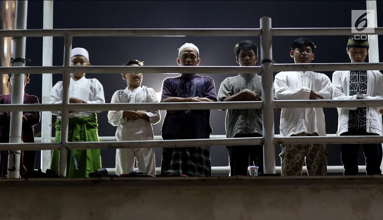 Sejumlah warga melaksanakan salat tarawih di atas JPO Musala Miftahul Jannah di Kawasan Pasar Gembrong, Jakarta, Kamis (17/5). Membludaknya jemaah yang hadir mengakibatkan mereka meluber hingga ke badan jalan dan JPO. (Liputan6.com/JohanTallo)