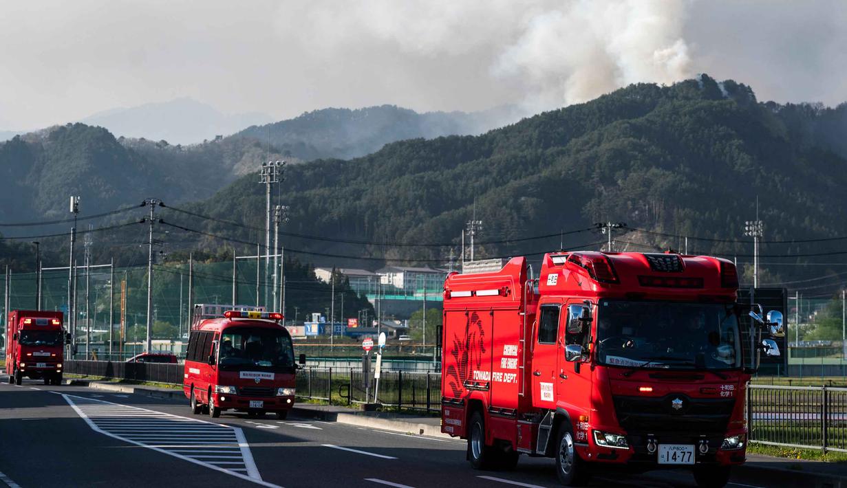 Sebelumnya, kebakaran hutan hebat juga pernah terjadi di Prefektur Oita, Kyushu, Jepang pada November 2025 yang menghanguskan lebih dari 170 bangunan. Tampak dalam foto, mobil pemadam kebakaran berpindah ke lokasi baru sementara asap terlihat di latar belakang kota Otsuchi, Prefektur Iwate, Jepang pada Sabtu 25 April 2026. (ANDREW CABALLERO-REYNOLDS/AFP)
