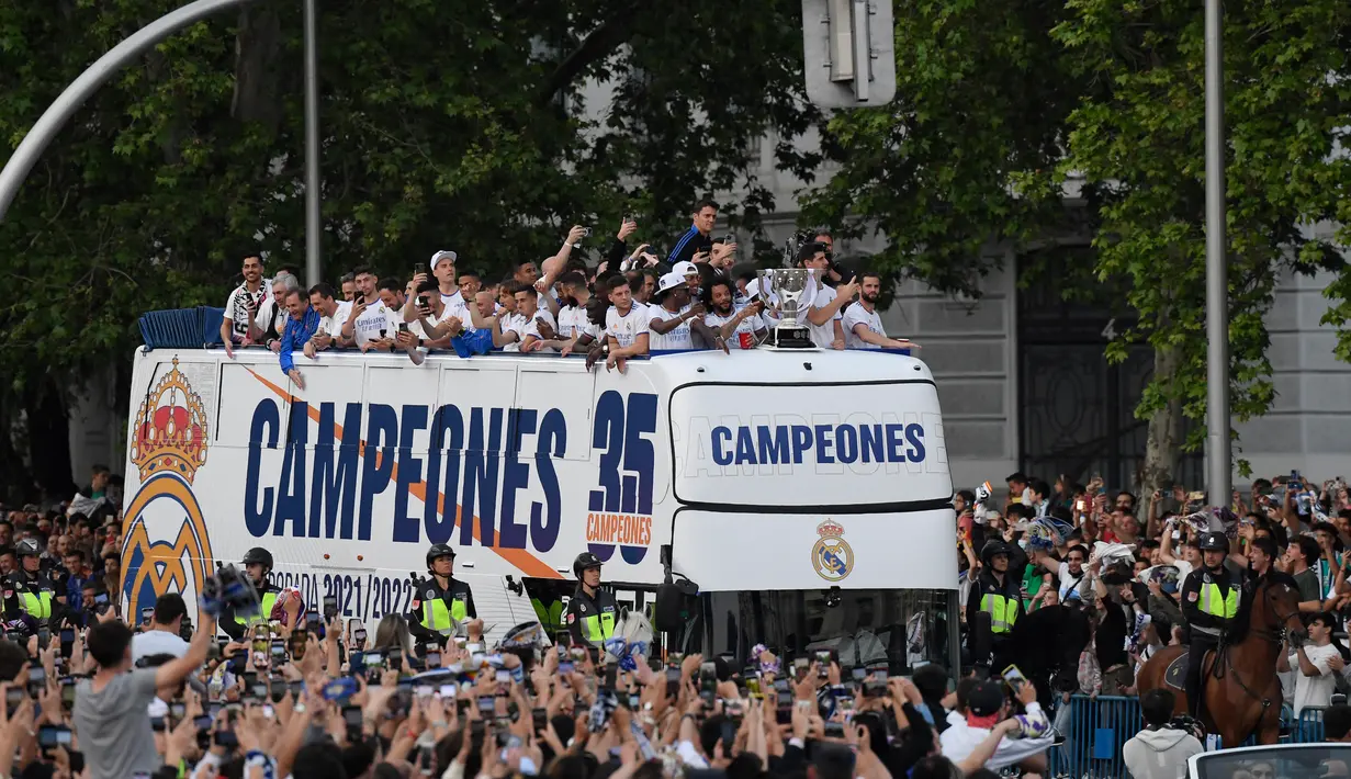 <p>Para pemain Real Madrid merayakan trofi La Liga Spanyol di atas bus di alun-alun Plaza Cibeles di Madrid pada 30 April 2022. Real Madrid mengamankan gelar La Liga ke-35  setelah kemenangan kandang 4-0 atas Espanyol. (AFP/Oscar Del Pozo)</p>