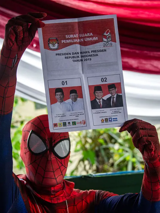 Petugas Kelompok Penyelenggara Pemungutan Suara (KPPS) berkostum superhero Spiderman menunjukkan surat suara Pemilu 2019 di sebuah TPS di Surabaya, Jawa Timur, Rabu (17/4). (Juni Kriswanto/AFP)