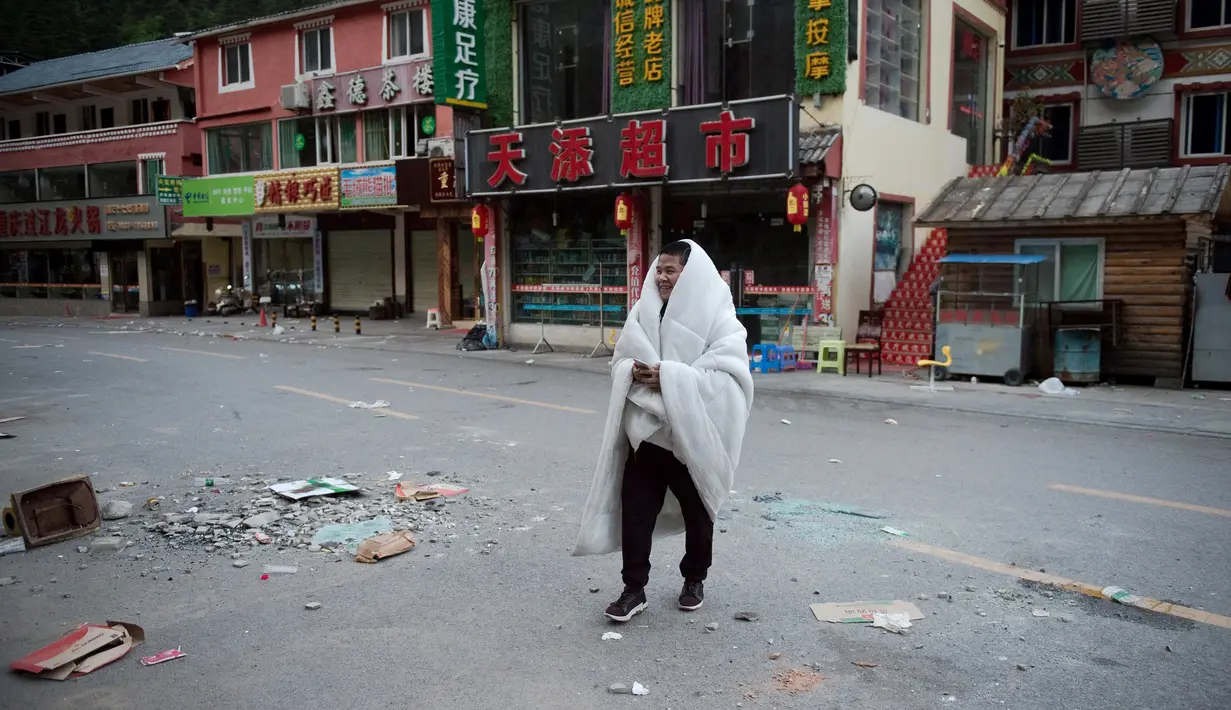 Warga berjalan-jalan setelah tidur di luar rumahnya di Zhangzha, provinsi Sichuan, China barat daya, Kamis (10/8). Ratusan warga memilih menghabiskan malam di luar rumah usai terjadinya gempa 6,5 SR yang menewaskan belasan orang (Nicolas ASFOURI/AFP)