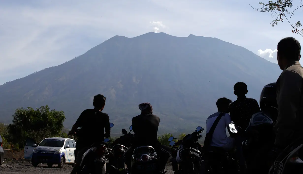 Penduduk mengamati Gunung Agung dari Desa Kubu, Kabupaten Karangasem, Bali, Rabu (11/10). Menurut BNPB, aktivitas vulkanik Gunung Agung masih tinggi sehingga PVMBG masih menetapkan status awas sejak 22 September lalu hingga saat ini. (AP/Firdia Lisnawati)