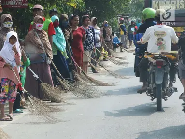 Sejumlah penyapu koin kali Sewo menunggu di sepanjang pinggir jalan, Subang, Jawa Barat, Sabtu (7/1). Mereka menunggu pengendara yang lewat melempar koin ke jalan. (Liputan6.com/Helmi Afandi)